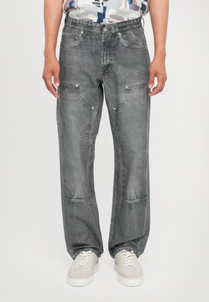 Grå denimjeans med avslappet passform, som har flere lommer og en lett slitt tekstur. Parret med hvite joggesko.