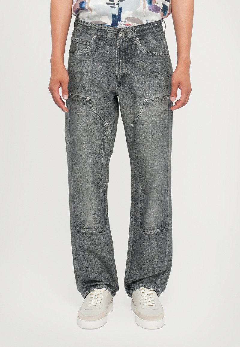 Grå denimjeans med avslappet passform, som har flere lommer og en lett slitt tekstur. Parret med hvite joggesko.