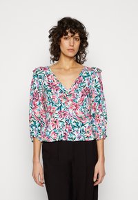 Blusa floral com um decote em V, apresentando padrões florais em tons de rosa, azul e verde sobre um fundo claro, e mangas 3/4 com punhos elásticos.