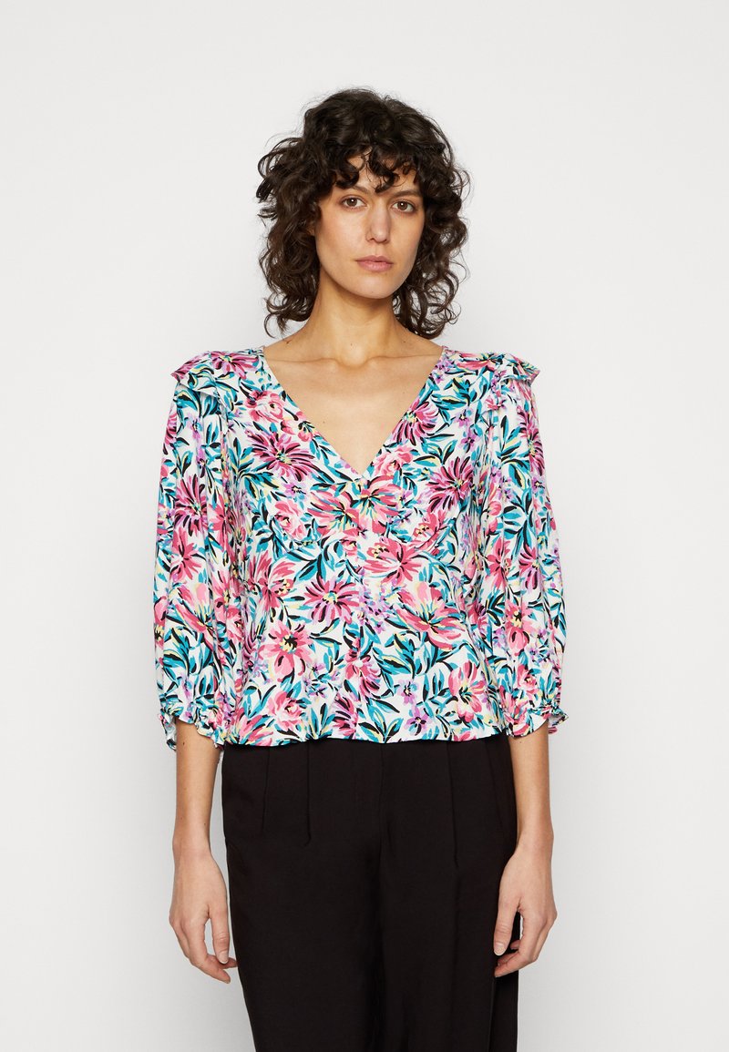 Blusa floral com um decote em V, apresentando padrões florais em tons de rosa, azul e verde sobre um fundo claro, e mangas 3/4 com punhos elásticos.