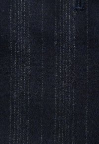 Tengerés szövet függőleges csíkokkal, texturált felület, puha, gyapjúra emlékeztető anyag, enyhe fényességgel és finom részletekkel világosabb szálakban.