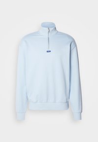 Sudadera con cremallera de color azul claro, con un cuello alto, puños y dobladillo acanalados, que presenta una pequeña etiqueta azul con "HUGO" en la parte frontal.
