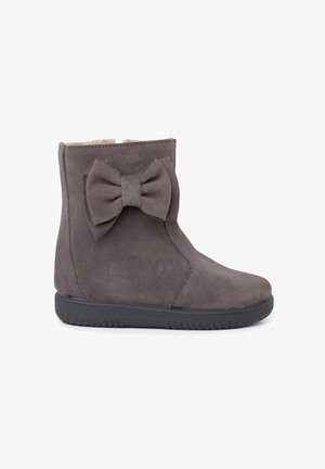 Stivale alla caviglia in suede grigio con un grande fiocco decorativo di lato, fodera interna morbida e suola in gomma nera.