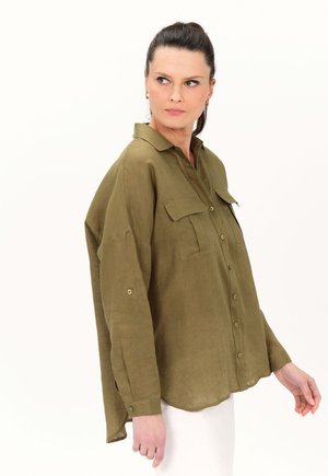 Camicia verde oliva con bottoni, due tasche sul petto, tessuto morbido, maniche lunghe e orlo arrotondato. Tessuto leggero con una vestibilità rilassata.