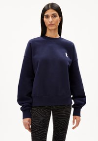 Navy blue sweatshirt made of cotton blend, featuring a crew neck, dropped shoulders, and a small white ribbon logo on the chest.