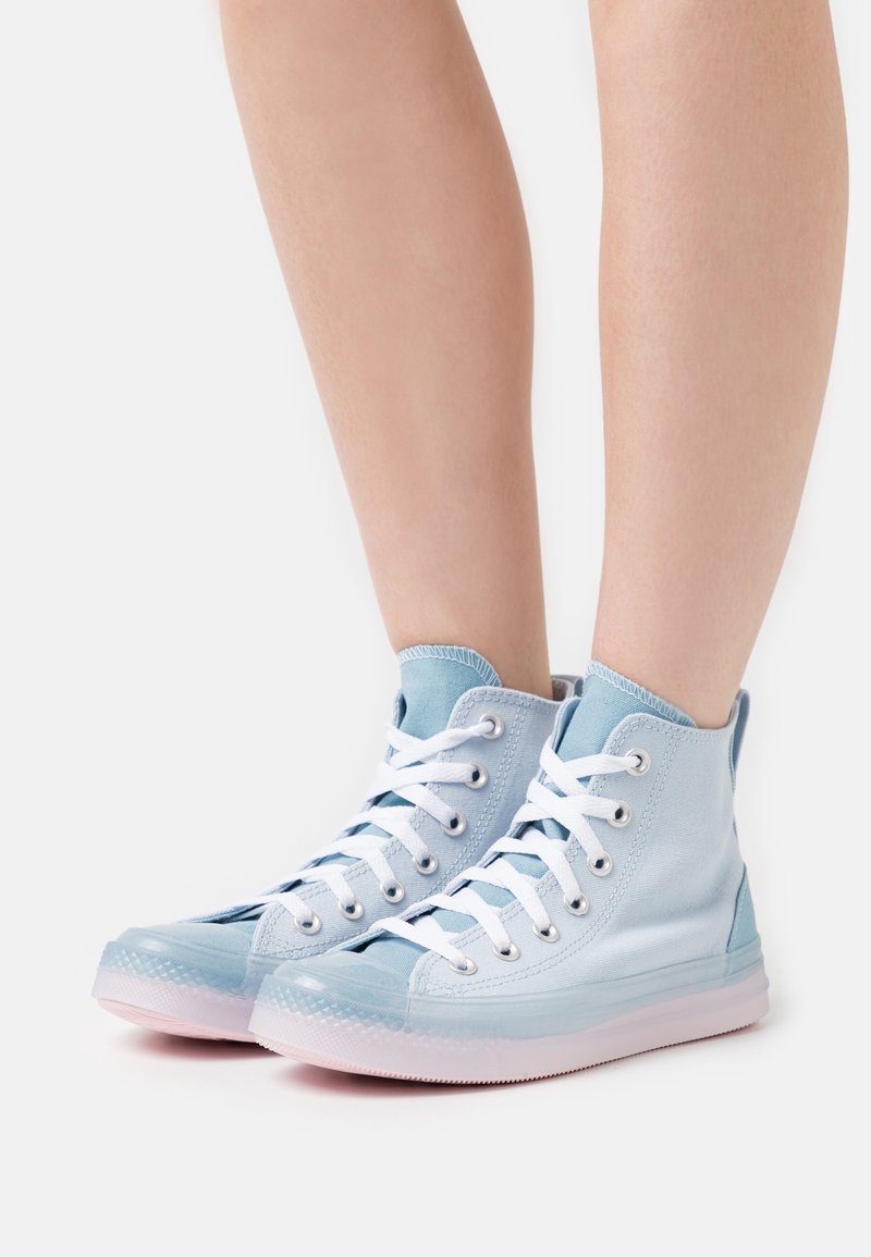 Ljust blå högskurna sneakers i canvas, med vita snören, silverfärgade ögla och en genomskinlig gummisula.