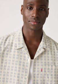 Korte mouw knoopshirt in lichtcrème met een blauw ruitpatroon, beschikt over een borstzak en is gemaakt van ademend materiaal.