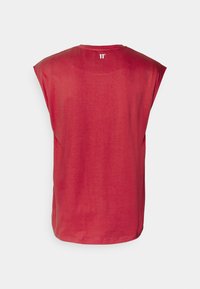 T-shirt senza maniche rossa con colletto rotondo, realizzata in tessuto morbido. Presenta una sottile trama melange e un piccolo logo all'altezza del collo sul retro.