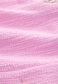 Close-up of textured pink fabric with a soft, knitted pattern and subtle color variations.