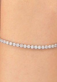 Bracciale tempestato di diamanti, con pietre rotonde e trasparenti incastonate in una delicata fascia d'argento, strettamente aderente alla pelle. Lieve luccichio messo in risalto.