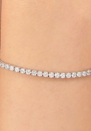 Bracciale tempestato di diamanti, con pietre rotonde e trasparenti incastonate in una delicata fascia d'argento, strettamente aderente alla pelle. Lieve luccichio messo in risalto.