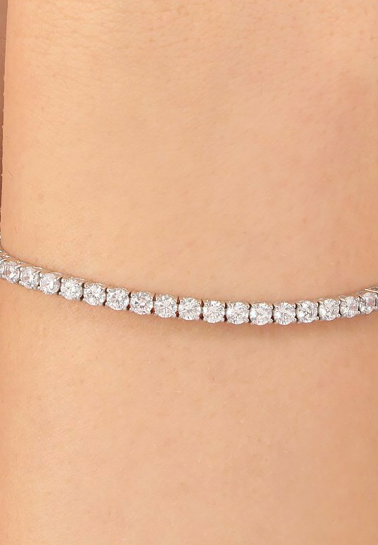 Bracciale tempestato di diamanti, con pietre rotonde e trasparenti incastonate in una delicata fascia d'argento, strettamente aderente alla pelle. Lieve luccichio messo in risalto.