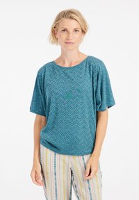 Turkio spalvos trumpa rankovė sėdanti viršutinė dalis su žuvies kaulų raštu ir subtiliais žaliais akcentais, derinama su raštuotomis pastelinių spalvų dryžuotomis kelnėmis.