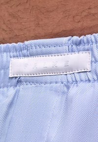 Lichtblauw patroonstof met een visgraatmotief. Voorzien van een elastische tailleband en een wit label met daarop het geperste woord "FALKE".