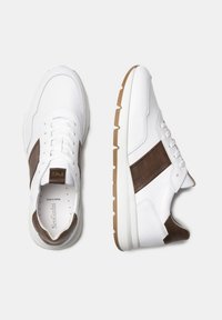 Sneakers bianchi in pelle con dettagli marroni, texture liscia, design con lacci e suola in gomma leggera con motivo a zigzag.