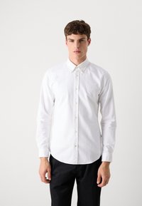 Witte lange mouw button-up shirt met een puntkraag, voorzien van een subtiele logo op de borst en een recht model, gecombineerd met donkere broek.