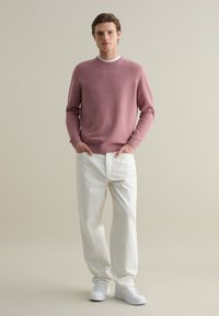 Light pink knit sweater with a crew neckline, paired with white wide-leg trousers and white sneakers. Simple design, minimal texture.