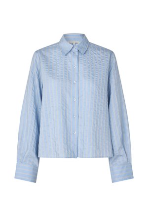 Jasnoniebieska koszula na guziki z białymi pionowymi paskami, kołnierzykiem i długimi rękawami zakończonymi mankietami. Gładka tkanina o uporządkowanym kroju.