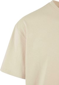 Beige katoen t-shirt met een ronde halslijn, korte mouwen en een gladde, zachte textuur. Schoon, minimalistisch ontwerp zonder zichtbare patronen.