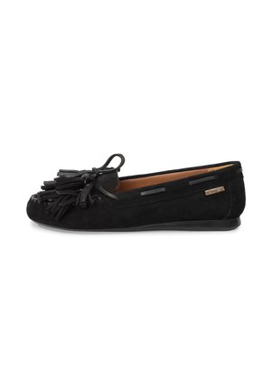 Mocasín negro de ante con detalles de borlas y una pequeña etiqueta de marca en el lateral, con suela plana y punta redondeada.