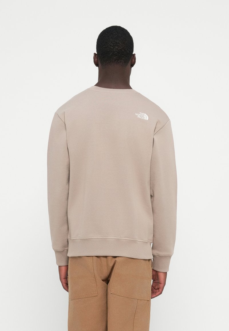 Beige Sweatshirt mit gerippten Bündchen und Saum, versehen mit einem kleinen weißen Logo auf der Rückseite. Aus weichem Material gefertigt, mit entspanntem Schnitt.