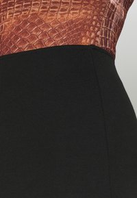 Body přiléhající k tělu s texturovaným oranžovo-hnědým vrškem s hadím vzorem a hladkým černým spodkem; design s vysokou elasticitou a dokonalým střihem.
