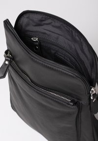 Black leather bag with silver zipper, featuring a textured finish. Includes an inner pocket and a smooth lining. Compact rectangular shape.