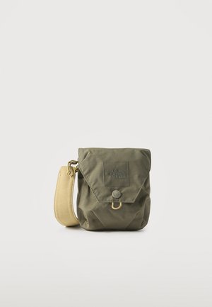 Petit sac bandoulière vert olive avec fermeture à rabat, patch de marque, bouton-pression et large sangle beige réglable.