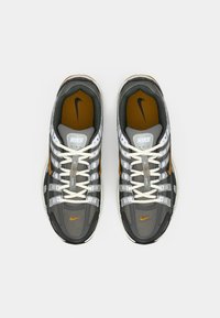 Γκρίζα και πορτοκαλί Nike αθλητικά παπούτσια με διχτυωτό πάνω μέρος, λευκές κορδόνες και μοτίβο στη σόλα. Διαθέτουν ασημένιες λεπτομέρειες και έντονο λογότυπο.