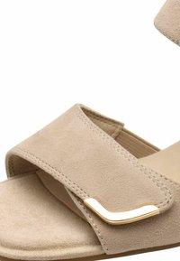 Beige Wildleder-Sandale mit zwei breiten Riemen, minimalistischen goldenen Hardware-Akzenten und einem konturierten Fußbett mit weicher Textur.