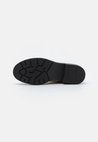 Black rubber sole with deep tread, textured for traction. Smooth beige upper with minimal design and no visible branding or accents.