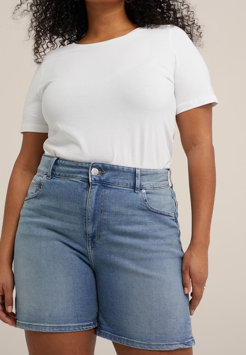 Vit kortärmad skjorta i kombination med ljusblå denimshorts. Shortsen har hög midja, framfickor och en slät yta.