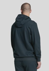 Dunkelgr�üne Kapuzenjacke mit einer großen, verstellbaren Kapuze, gerippten Bündchen und strukturiertem Stoff. Glatte Oberfläche mit entspannter Passform für Komfort.