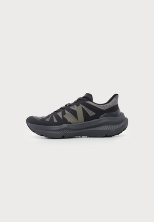 Zapatilla deportiva negra y gris con suela gruesa acolchada y gran logotipo "V" de color verde oscuro en el lateral.