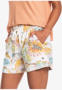 Shorts à motif floral avec un fond blanc, ornés de feuilles tropicales éclatantes en jaune, rose et vert. Taille élastique avec cordon de serrage et poches.
