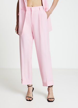 Pantaloni a gamba larga di colore rosa chiaro con vestibilità sartoriale, risvolti piegati e tasche frontali, abbinati a tacchi neri con cinturini.