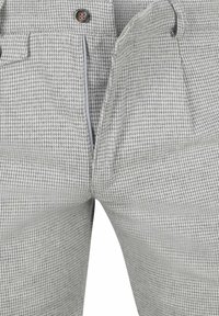 Grijze houndstooth broek met ritssluiting, knoopsluiting en twee voorkanten zakken. Materiaal heeft een gestructureerd patroon over de hele stof.