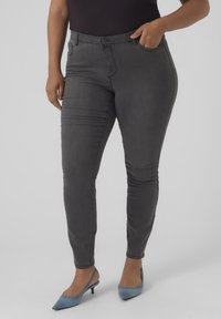 Dark grey skinny jeans made of stretchy cotton blend fabric, featuring five pockets, belt loops, and a zip fly with button closure.