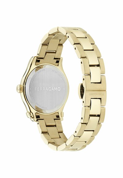 Reloj de pulsera de metal tono dorado con parte trasera de acero inoxidable grabada con "Ferragamo", pulsera de eslabones y cierre desplegable.