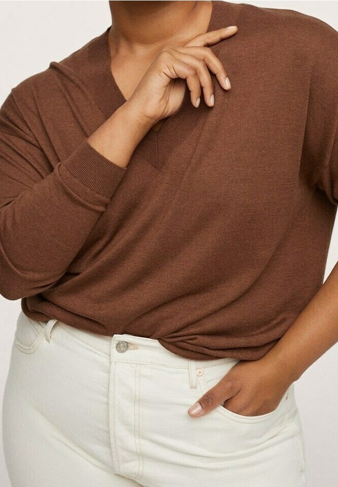 Pull en v marron à manches longues, en tissu doux, coupe décontractée, associé à un jean taille haute blanc, mettant en valeur des boutons sur le devant et des détails de poches.