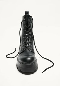 Czarne skórzane botki za kostkę z okrągłym noskiem, podwyższoną platformą i metalowymi oczkami na sznurówki. Posiadają boczny zamek błyskawiczny oraz luźne czarne sznurówki.