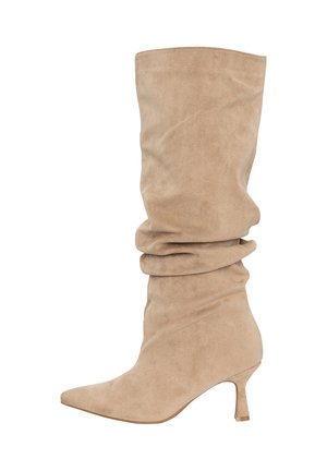 Bota beige de ante holgada hasta la rodilla con punta afilada y tacón medio delgado.