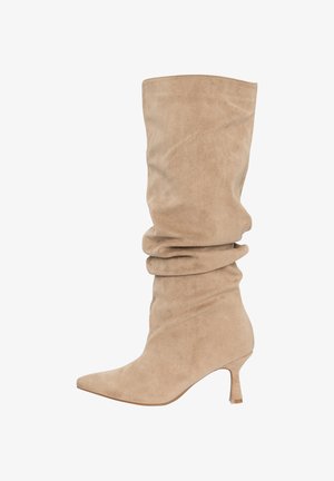 Bota beige de ante holgada hasta la rodilla con punta afilada y tacón medio delgado.
