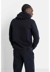 Marinblå hoodie med dragsko i huvan, ribbade muddar och nederkant. Mjuk bomullsmaterial, avslappnad passform, med en känguruficka.