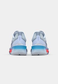 Zapatillas deportivas con un diseño ligero en azul claro y gris, con un talón texturizado y detalles en la suela de múltiples colores.