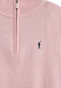 Ljust rosa zip-up sweatshirt tillverkad av mjukt tyg med ribbat krage. Har en liten svart logotyp av en golfare på vänster bröst.