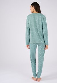 Ensemble de pyjama vert clair avec un motif de croissant de lune blanc ; haut à manches longues et pantalon fuselé en tissu doux. Design simple et décontracté.