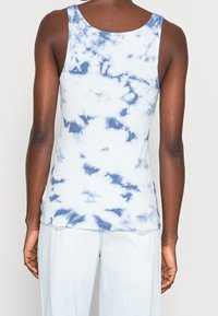 Débardeur côtelé de couleur bleu clair avec un motif tie-dye bleu foncé. Présente un col rond et des bretelles larges.