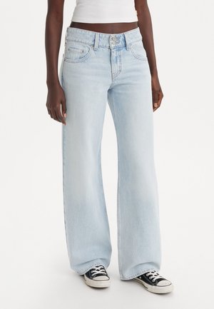 Lys blå vid jeans laget av denim, med høy liv, frontlommer og knappelukking. Kombinert med svarte lave sneakers.