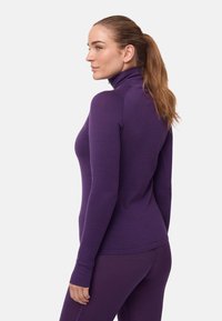 Lila langärmeliges Oberteil mit hohem Kragen und figurbetontem Schnitt, aus weichem Material gefertigt, mit Daumenlöchern und glatter Oberfläche.
